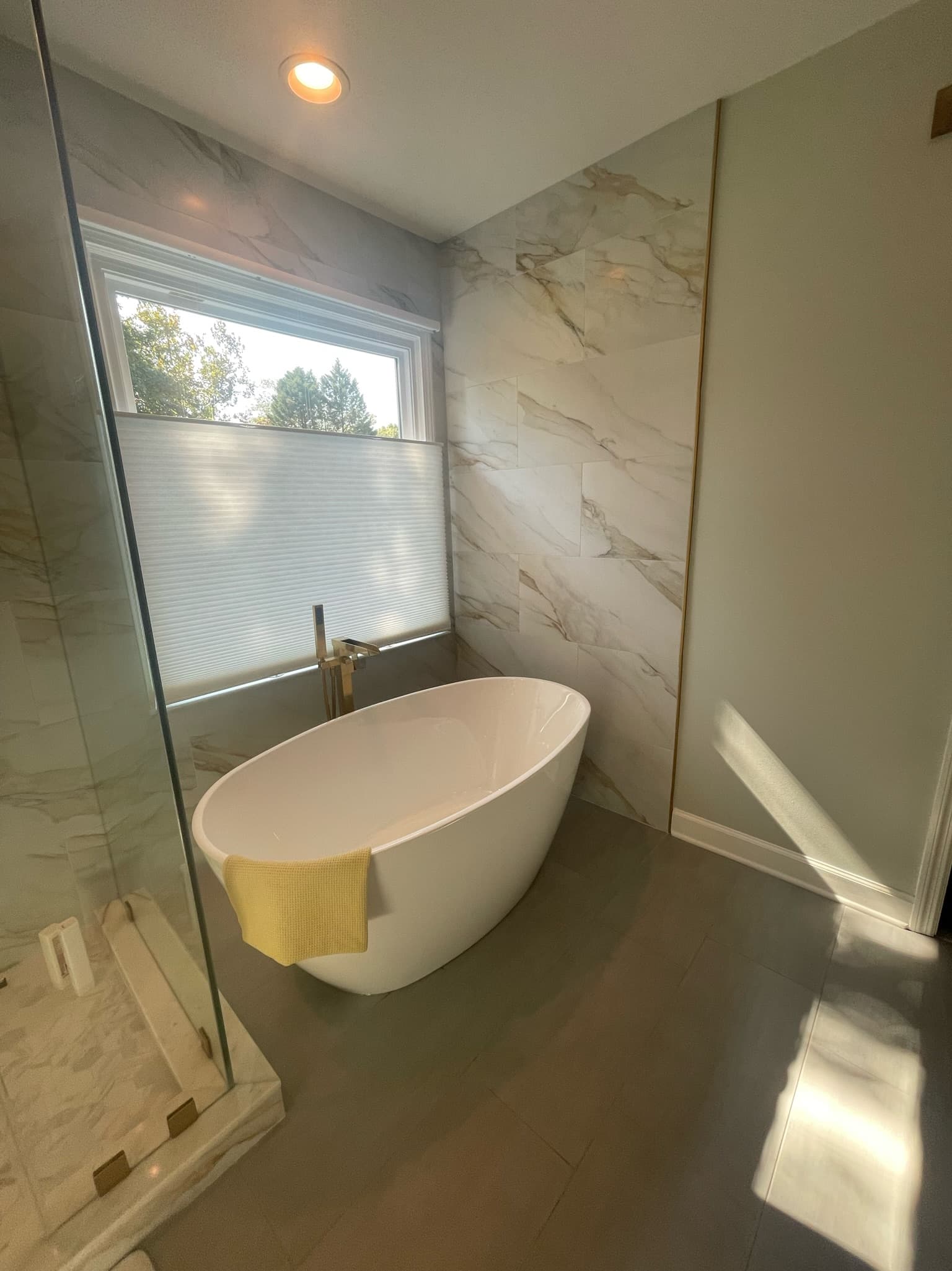 Master bathroom remodel with freestanding tub, marble-look tile walls, glass shower enclosure, and large-format floor tile in Charlotte NC